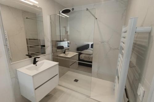 une salle de bain blanche avec un lavabo et une douche dans l'établissement Naturiste Cap d'Agde Héliopolis O 11, au Cap d'Agde