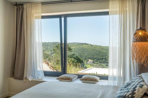 a bedroom with a large window with a view at Viladraga - Casa da Adraga in Colares