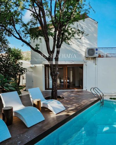 a pool with chairs and a tree next to a house at Sense of Haiya in Chiang Mai