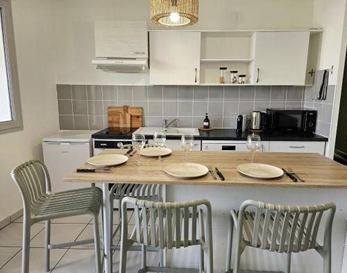 uma cozinha com uma mesa com cadeiras e copos de vinho em Superbe Apt 2 ch, terrasse, WIFI, parking gratuit em Toulouse