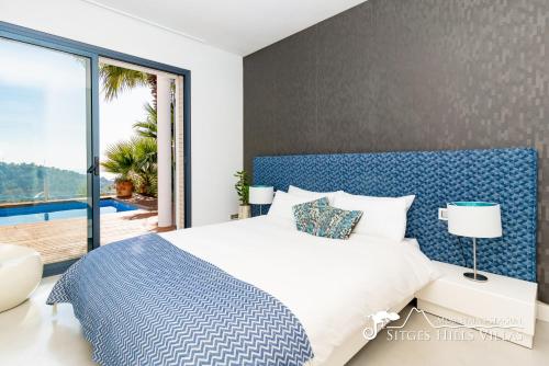 een slaapkamer met een blauw en wit bed en een raam bij Super Villa Oasis Fab Sea and Sitges View with Private Pool and Air Conditioning in Sitges