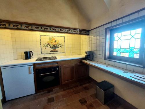 Il comprend une petite cuisine avec une cuisinière et une fenêtre. dans l'établissement Au Jardin Secret proche Center Parcs, à Pouançay