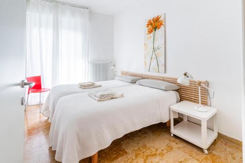 a white bedroom with two beds and a table at Quattro Fontane Apartment in Venice-Lido