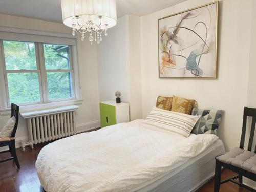 a bedroom with a white bed and a chandelier at A bright and tidy room in midtown near subway in Toronto