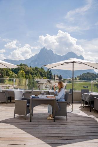 カステルロットにあるHotel Alpenfloraの傘下のテーブルに座る女性