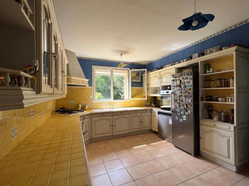  La cuisine est équipée de placards blancs et d'un réfrigérateur. dans l'établissement Villa avignon, à Avignon