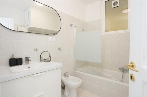 une salle de bain blanche avec un lavabo et un miroir dans l'établissement Somptueux 2 pièces Vue époustouflante Mer -Parking, à Roquebrune-Cap-Martin