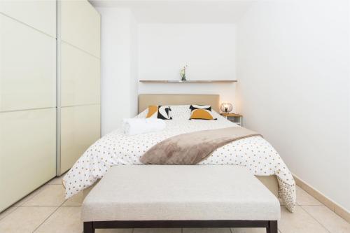 - une chambre blanche avec un lit et un banc dans l'établissement Somptueux 2 pièces Vue époustouflante Mer -Parking, à Roquebrune-Cap-Martin