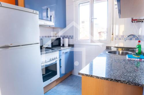 a kitchen with white appliances and blue cabinets at Apto Niemeyer - Avilés centro in Avilés