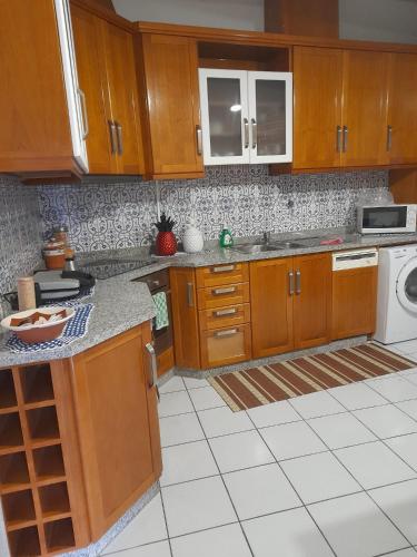 a kitchen with wooden cabinets and a white tile floor at O Cantinho da Auzenda in Torre de Moncorvo