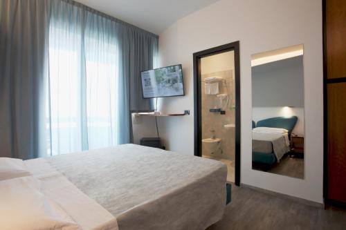 een hotelkamer met een bed en een spiegel bij Hotel Ali d'Oro in Rimini