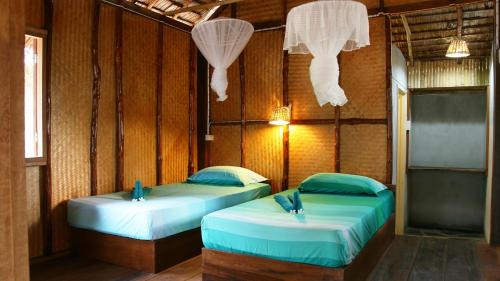 two beds in a room with wooden walls at Sea Culture in Ko Lanta