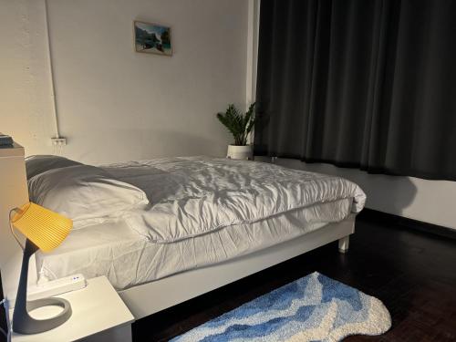 a bedroom with a bed and a table with a lamp at Before We Go Hostel Donmueang in Ban Ko