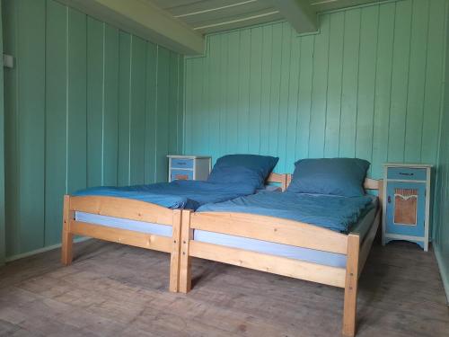 a wooden bed with blue sheets in a room at Chaloupka Pod jabloněmi in Chřibská