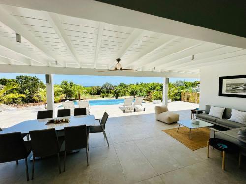 a living room with a table and chairs and a pool at Villa Tropical Heaven - Terres Basses in Les Terres Basses