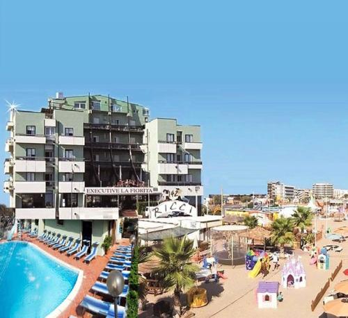 a large hotel with a swimming pool next to a beach at Hotel Executive La Fiorita in Rimini