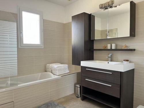 une salle de bain avec un lavabo, une baignoire et un miroir dans l'établissement Villa climatisée avec piscine, à Baillargues