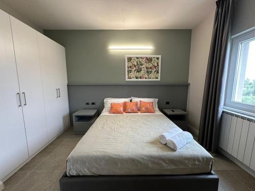 a bedroom with a bed with orange pillows and a window at Evergreen Laguna Vain-Lezhe in Lezhë