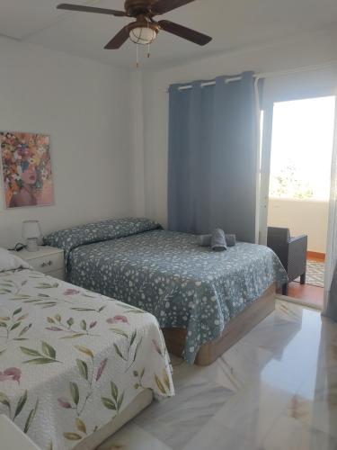 - une chambre avec 2 lits et un ventilateur de plafond dans l'établissement Apartamento Sunbeach, à Torremolinos