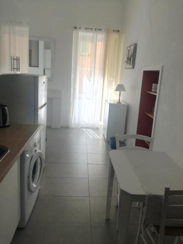 une cuisine avec une machine à laver et une table et une table et une chaise dans l'établissement Appartement au coeur de la citadelle, à Bastia