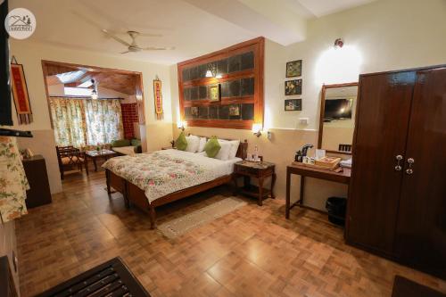 a bedroom with a bed and a desk in a room at Hotel Udechee Huts, McLeod Ganj in McLeod Ganj