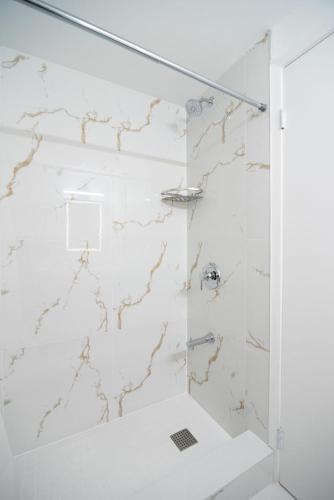 a bathroom with a shower with white tiles at Diplomat Inn in Niagara Falls