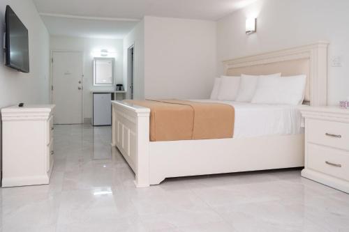 a white bedroom with a large bed and a kitchen at Diplomat Inn in Niagara Falls