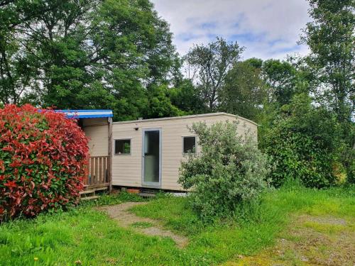 a small white house in a field with a bush at Gîtes et Camping Hameau Nouste Temps in Castelnau-Magnoac