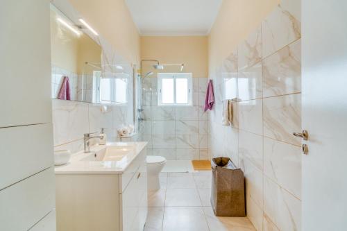a white bathroom with a sink and a toilet at Cantinho da Portada in Seixal