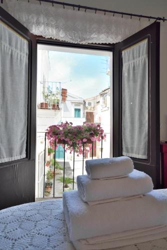 a stack of towels on a bed in front of a window at Case del Vicolo Stretto in Modica