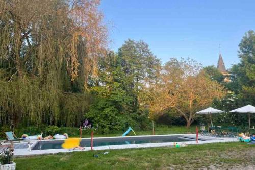 - une piscine dans un parc avec des parasols dans l'établissement Belle maison de famille Perche avec piscine, à Planches