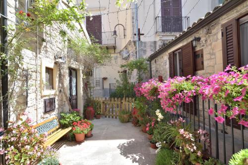 a courtyard with flowers and a bench and a fence at Case del Vicolo Stretto in Modica