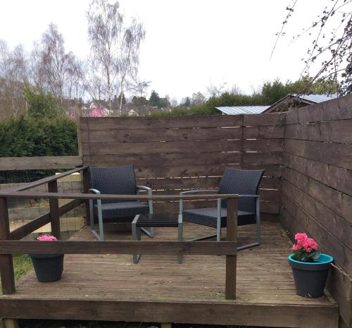 deux chaises et une table sur une terrasse en bois dans l'établissement 10 Rue Bardeau,Fougerolle du Plessis,France,53190, à Fougerolles-du-Plessis