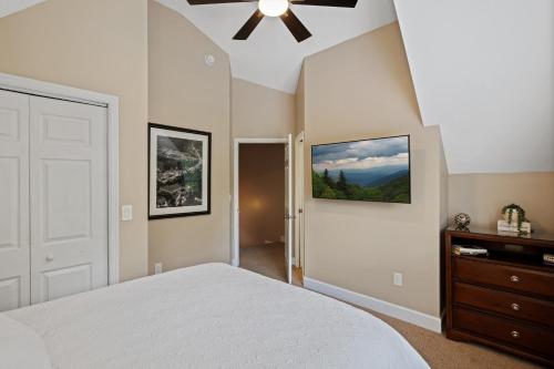 ein Schlafzimmer mit einem weißen Bett und einem Deckenventilator in der Unterkunft Little Bear Cottage is located only a half-mile away from downtown Gatlinburg! in Gatlinburg