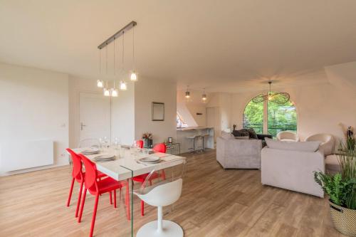 a living room with a table and red chairs at Appart 3 chambres avec parking privé et terrasse in Roubaix