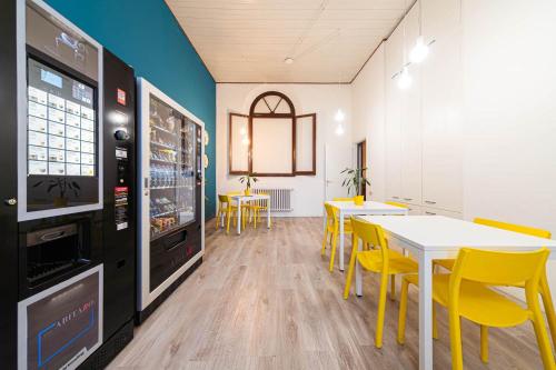 a dining room with yellow chairs and tables and a tv at Il Villaggio di ABITABO in Bologna