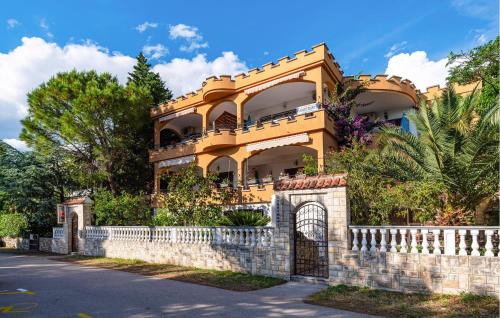 a yellow house with a fence in front of it at Stunning Apartment In Rovanjska in Rovanjska