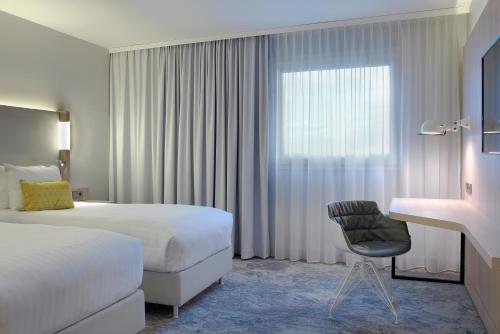 Habitación de hotel con cama, escritorio y ventana en The Jangle Hotel - Paris - Charles de Gaulle - Airport en Le Mesnil-Amelot