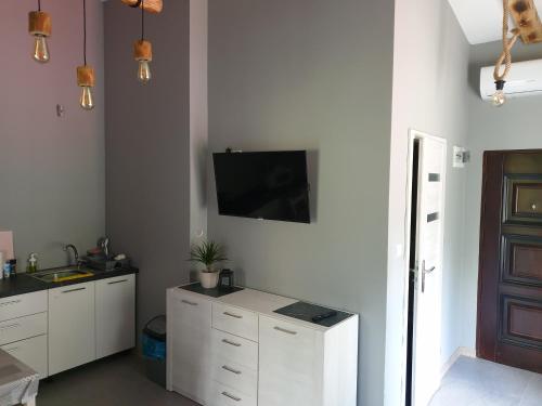 a kitchen with white cabinets and a tv on the wall at Apartament Pod Sosami 3 Noclegi OTW Borówno WLK Skarszewy in Skarszewy
