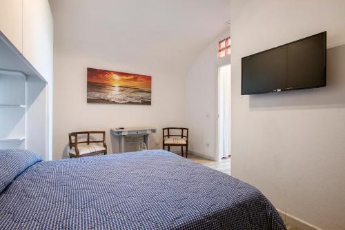 a bedroom with a bed and a flat screen tv on the wall at Appartamento con vista esclusiva sul Golfo d'Ischia in Ischia