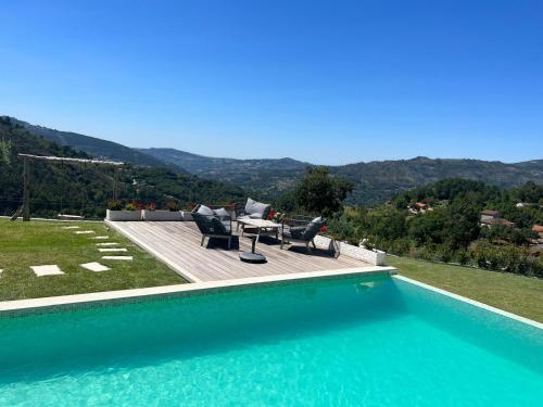 a swimming pool with chairs and a table on a hill at Quintinha da Mariana - Charming in the Douro Valley in Cinfães