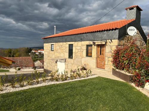 a stone building with an orange roof and a yard at Quintinha da Mariana - Charming in the Douro Valley in Cinfães