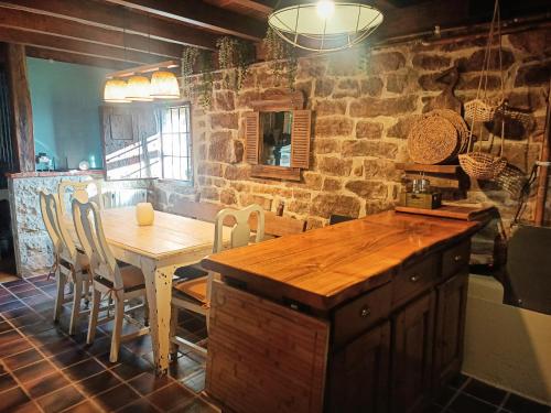 a kitchen with a table and chairs and a stone wall at La cabaña mirador de los Valles Pasiegos in Vega de Pas