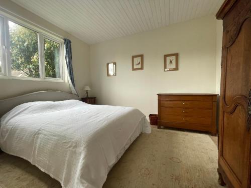 Un dormitorio con una cama y una cómoda y una ventana. en La Canuche Appartement avec jardin, en Pleine-Sève