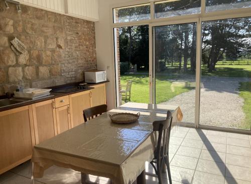 une cuisine avec une table et une grande fenêtre dans l'établissement La Canuche Appartement avec jardin, à Pleine-Sève