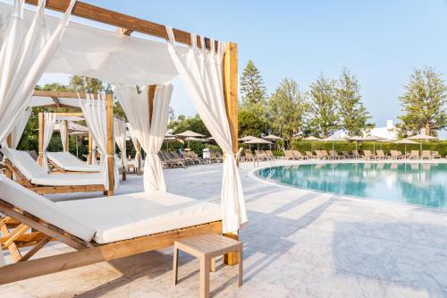 uma piscina de resort com cadeiras, uma cama e um baloiço em Jupiter Albufeira Hotel - Family & Fun - All Inclusive em Albufeira