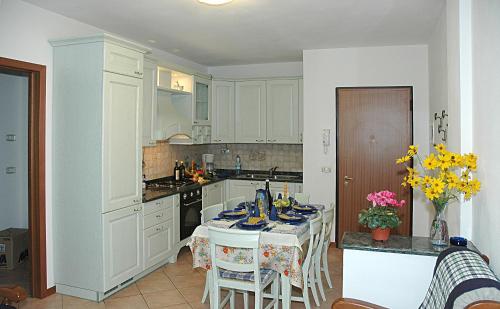 una cocina con armarios blancos y una mesa con sillas. en Appartamento Ai Tigli, en Caorle