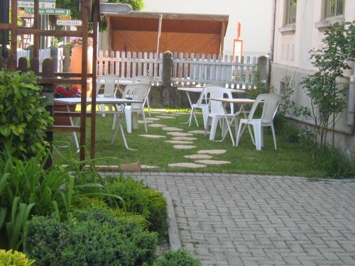 a patio with white chairs and tables in a yard at Hostellerie La Boheme in Roppenheim