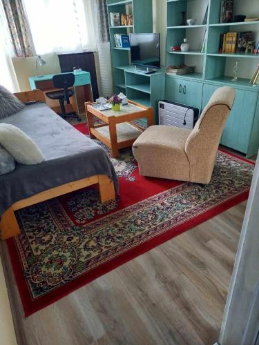 a bedroom with a bed and a chair and a table at Valéria Vendégház Hévíz in Hévíz