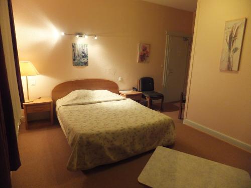 a hotel room with a bed and a lamp at Hostellerie La Boheme in Roppenheim